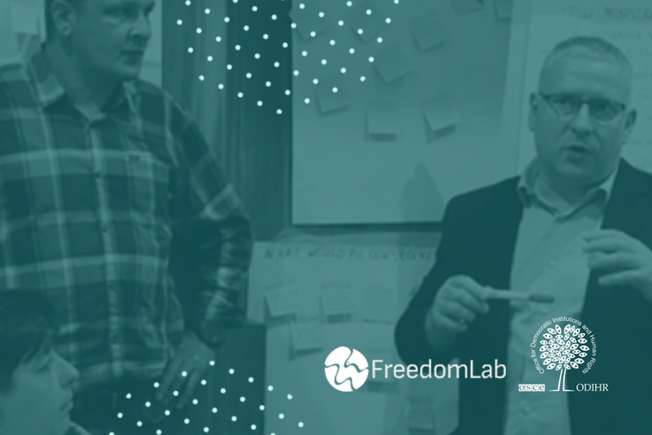 Two people in discussion with a backdrop of sticky notes and logos for FreedomLab.