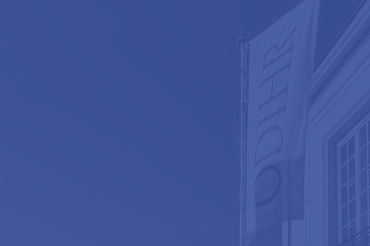 Blue monochrome photo of a building corner with a vertical flag reading "ODIHR."