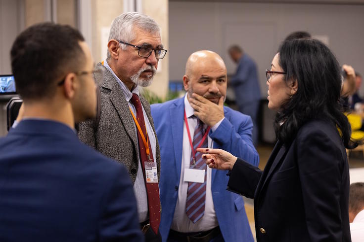 Group of four people in formal attire engaged in conversation at an indoor event.