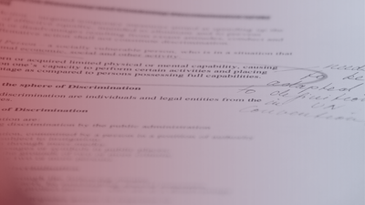 Legal document with handwritten notes, viewed at an angle, in soft red lighting.