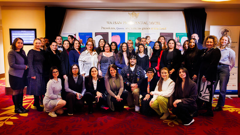 A group of people standing together in a conference room with a carpeted floor and colorful banners in the background.